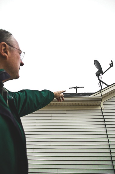 Neighborhood 11 resident Ed Pierce received a letter stating his satellite dishes are in violation of Sun City design guidelines and must be moved. Here he explains that the two dishes are positioned for optimal reception. Pierce questions why it’s taken the association so long to inform him that his dishes were in violation of the guidelines. He’s had the dish in the foreground on his roof for nine years. (Photo by Chris LaPelusa/Sun Day)