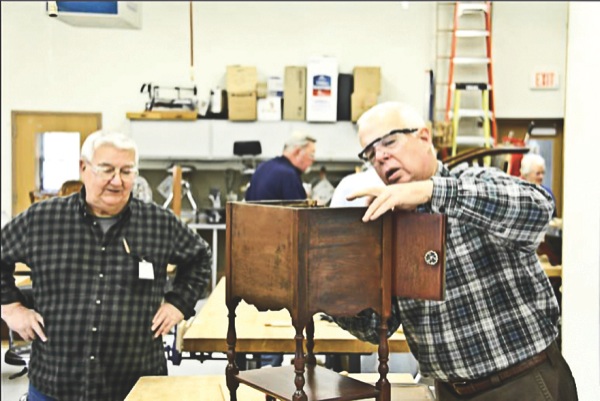 Gerry Macozzi and John Sterling work on a tobacco cabinet to reattach the top. (Photo provided)