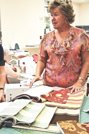 Jan Hoeft, owner of Interior Motives in Huntley, looks over fabric used by the Sew ‘N Sews of Sun City. Until recently, Hoeft did not know that the fabrics she donated to the group were turned into items for those in need. (Photo by Hannah Sturtecky/Sun Day)