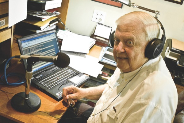 Samuelson poses in front of his home broadcast equipment. Samuelson is able to perform some afternoon updates for WGN radio from his Sun City home. (Photo by Mason Souza/Sun Day)