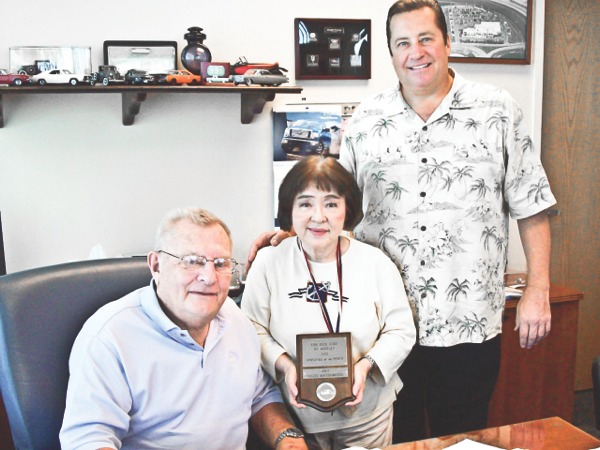 Sach Matsumoto (center) shows her July Employee of the Month plaque at Tom Peck Ford in Huntley. The Sun City resi- dent has worked at the dealership for seven years. (Photo provided)