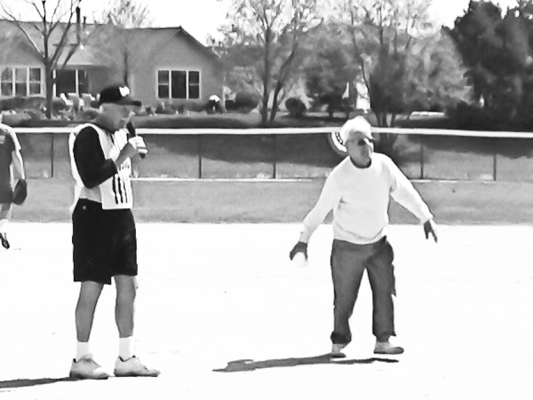 90-year-old Peter Karambelas (right) throws out the opening pitch of the season. Officiating is Softball League president Glenn Groebli. (Photo provided)