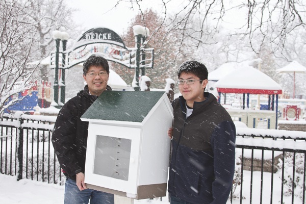 Eagle Scout Jarrod Khoo (right) with his father Chris displaying one of Jarrod’s handcrafted Little Free Libraries at its future spot in Deicke Park. (Photo by Chris LaPelusa/Sun Day)