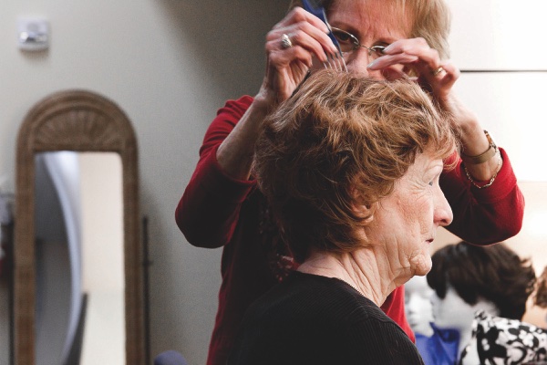 Backstage, Mary Reuter is outfited by Eira Michelutti (above, using pick) with various wigs for the performance.