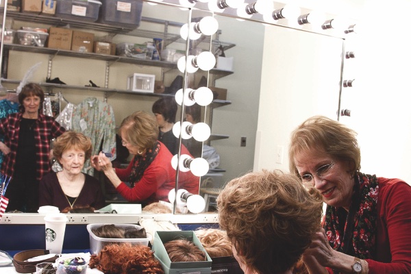 Eira Michelutti (right) affixes a wig to cast member Mary Reuter backstage in Drendel Ballroom. Mary Wyatt waits her turn behind. (Photos by Chris LaPelusa/Sun Day)