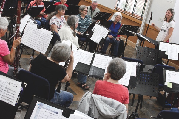 Ensemble director Pam Jorgensen (standing) shares a laugh with the band during a break in rehearsals.