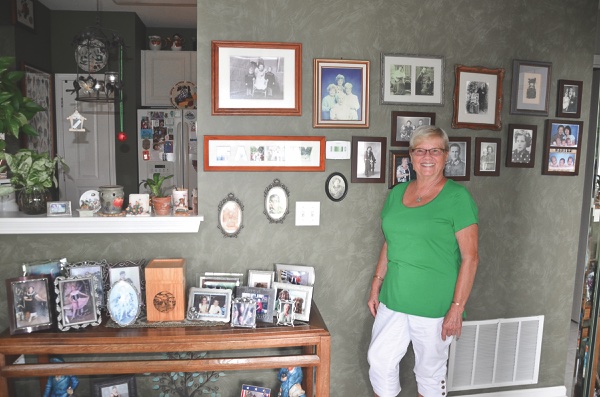 Margitta (Kitty) Rizzo stands before her family gallery wall in her home. (Photo provided)