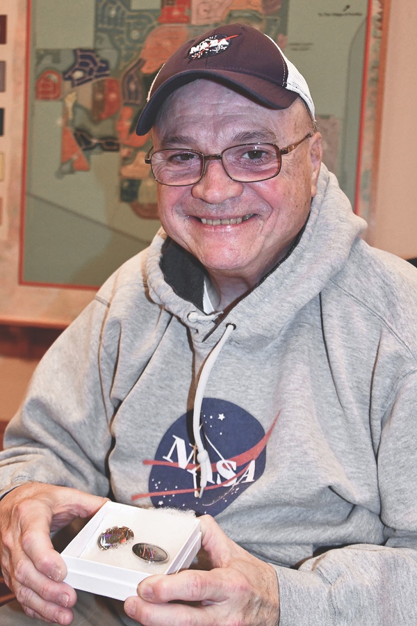 Ken Kozy holds two laser-cut pieces of nickel that contain large amounts of information set for a mission to the moon. (Photo by Christine Such/Sun Day)