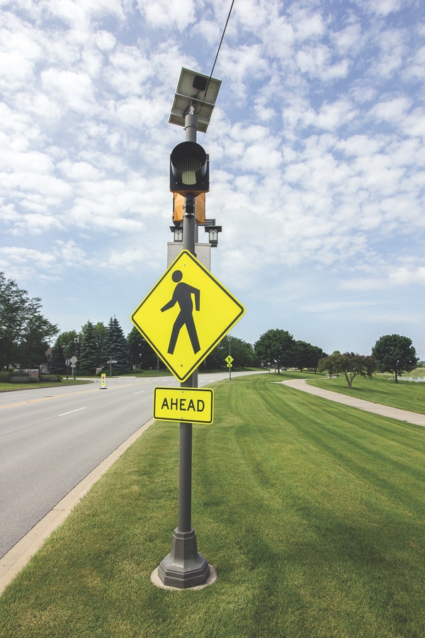 Flashing yellow lights, like this one near Wildflower Lake in Sun City, are becoming more common in McHenry County, offering additional safety for pedestrians. (Photo by Tony Pratt/Sun Day)