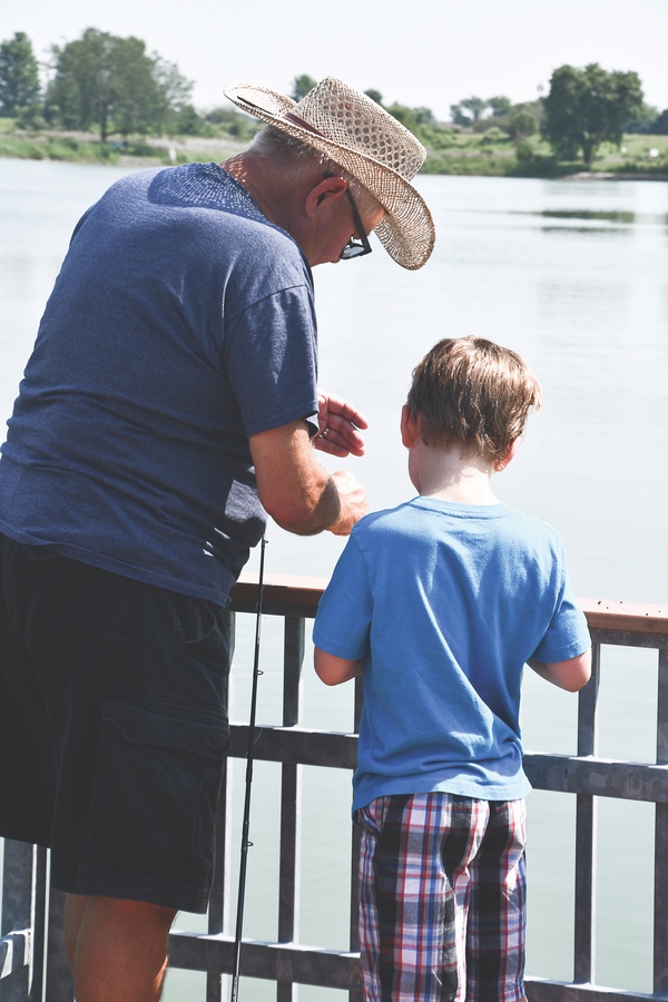 An Anglers’ Club member shows his grandson how to bait a hook.