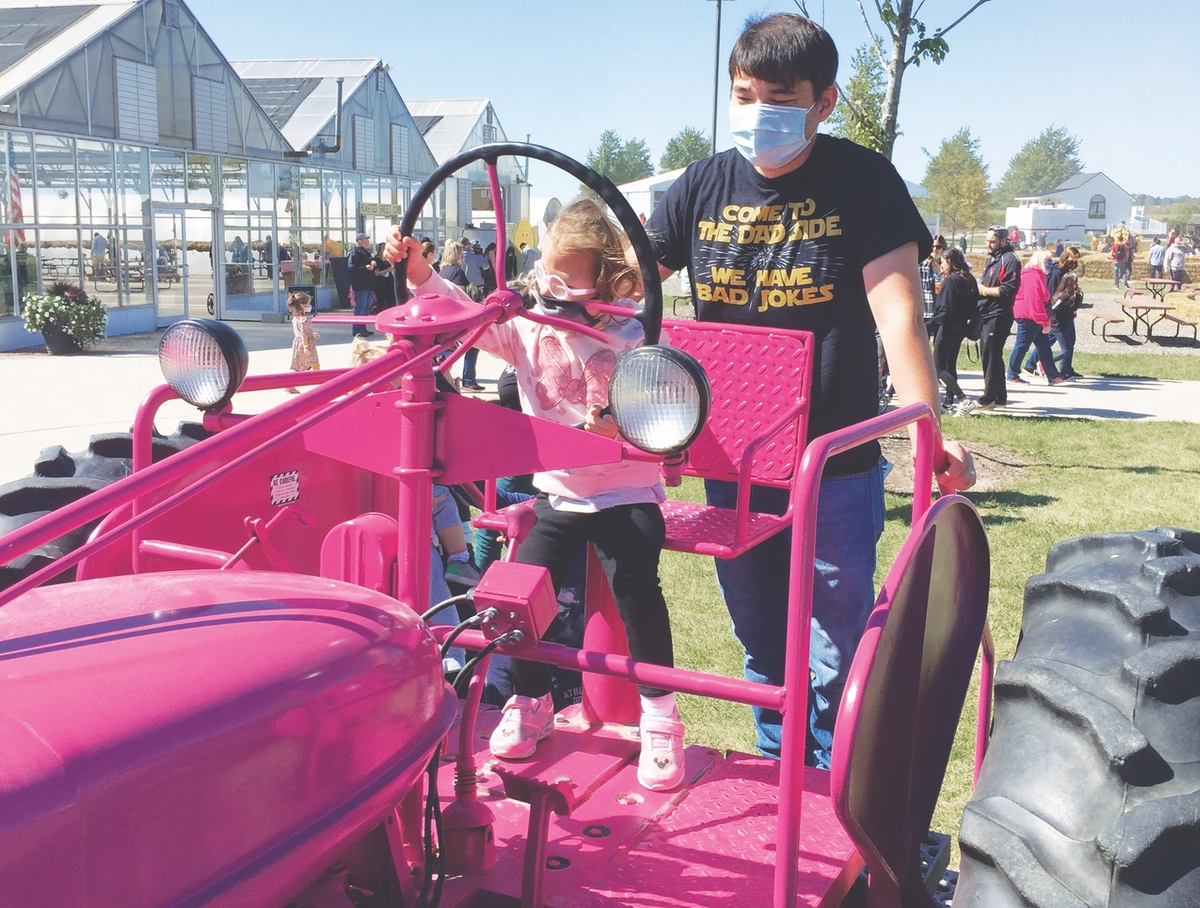 Danny Chriscoe of Volo keeps a watch on daughter Ellie, 3, as she takes a purple tractor for a drive Saturday at Goebbert’s Pumpkin Patch south of Huntley. (Photo by Gavin Maliska/My Huntley News)