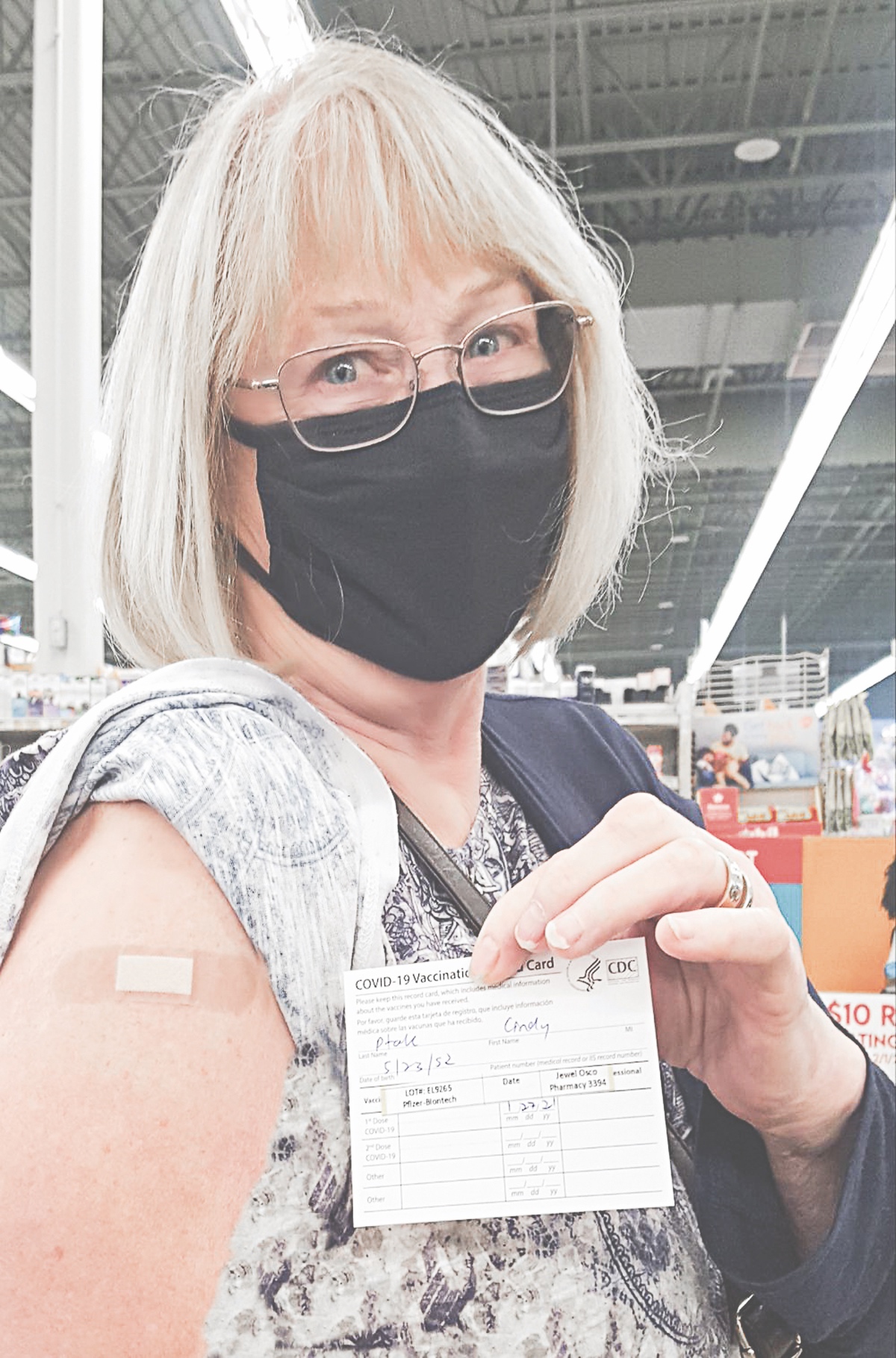 Sporting the bandaid from her shot, Sun City resident Cindy Ptak shows her vaccination card.