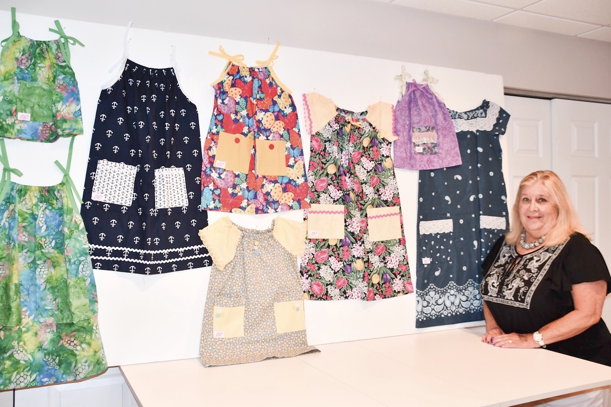 Dress A Girl member Sue Kamphausen poses with samples of dresses sewed for underprivelaged girls to keep them clothed and quite possibly keep them save from traffikers. (Photos by Christine Such/Sun Day)