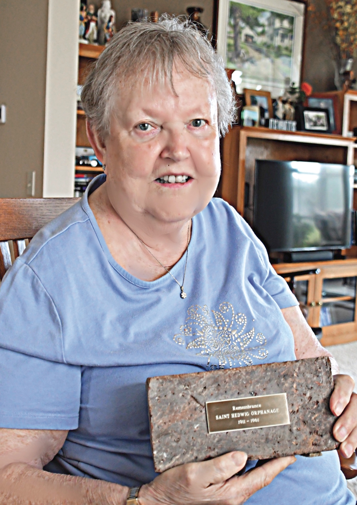 Sun City resident Joanie Berg was once known as Boney Bones to the other kids at St. Hedwig orphanage, where she lived for ten years from 1943 to 1953. Here she holds a brick from St. Hedwig. (Photo by Christine Such/My Sun Day News)