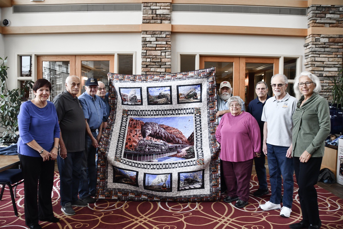 Members of the Sew N Sews Club hold the quilt that will be displayed the train club during open houses. (Photo by Christine Such/My Sun Day News)