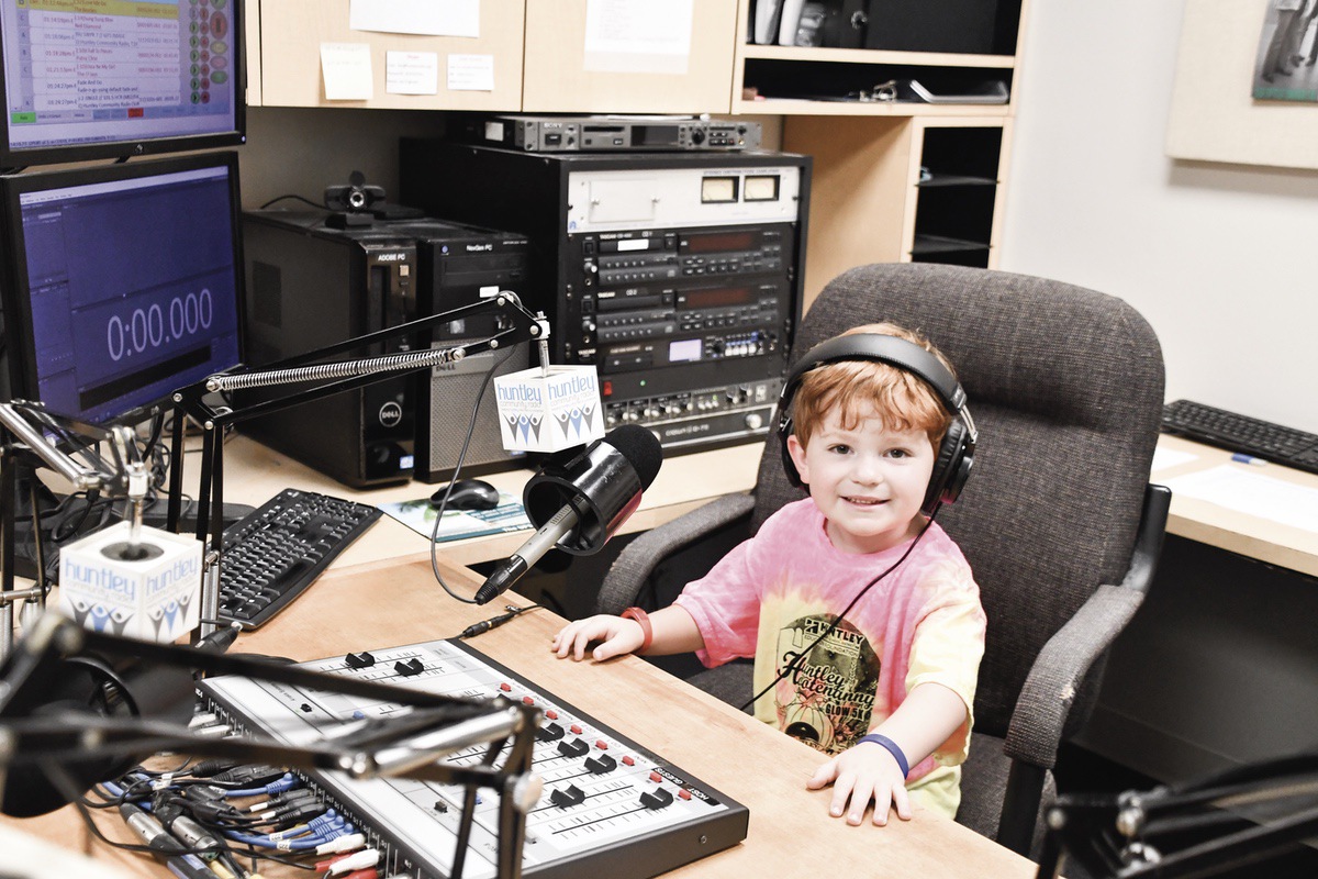 Lochlan Pedersen comfortable in the D.J. chair at Huntley radio Station. (Photo by Christine Such/My Sun Day News)