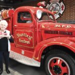 Sun City resident and artist Amy Rohr presents to Huntley Fire Chief Scott Ravagnie her sculpture of the restored fire engine. (Photo by Christine Such/My Sun Day News)