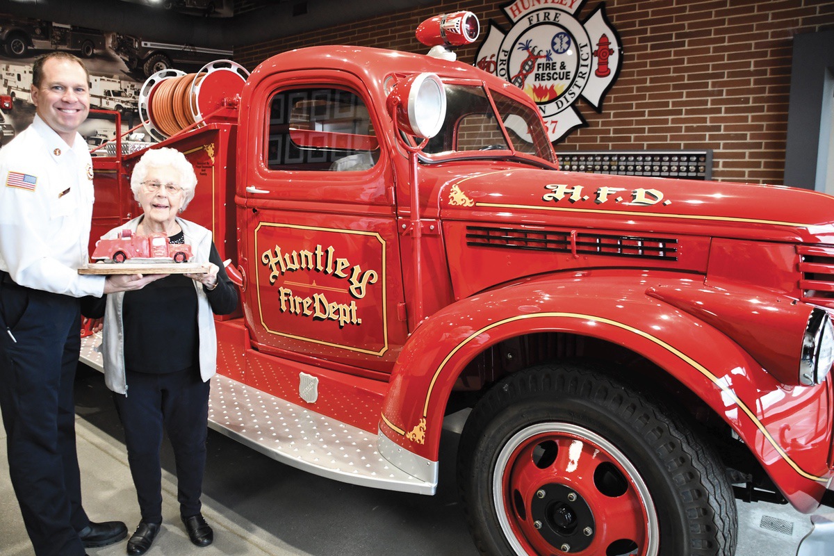 Sun City resident and artist Amy Rohr presents to Huntley Fire Chief Scott Ravagnie her sculpture of the restored fire engine. (Photo by Christine Such/My Sun Day News)