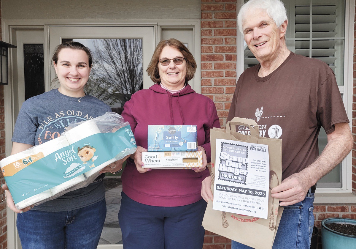 Grafton Food Pantry volunteer Rich Ford delivers a donation bag to Sun City resident Stacey Sadowski and her daughter Amanda, who have already been shopping for Stamp Out Hunger. (Photo provided)
