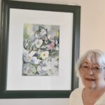 Arlene Terdina poses with her favorite watercolor painting. (Photo by Christine Such/My Sun Day News)