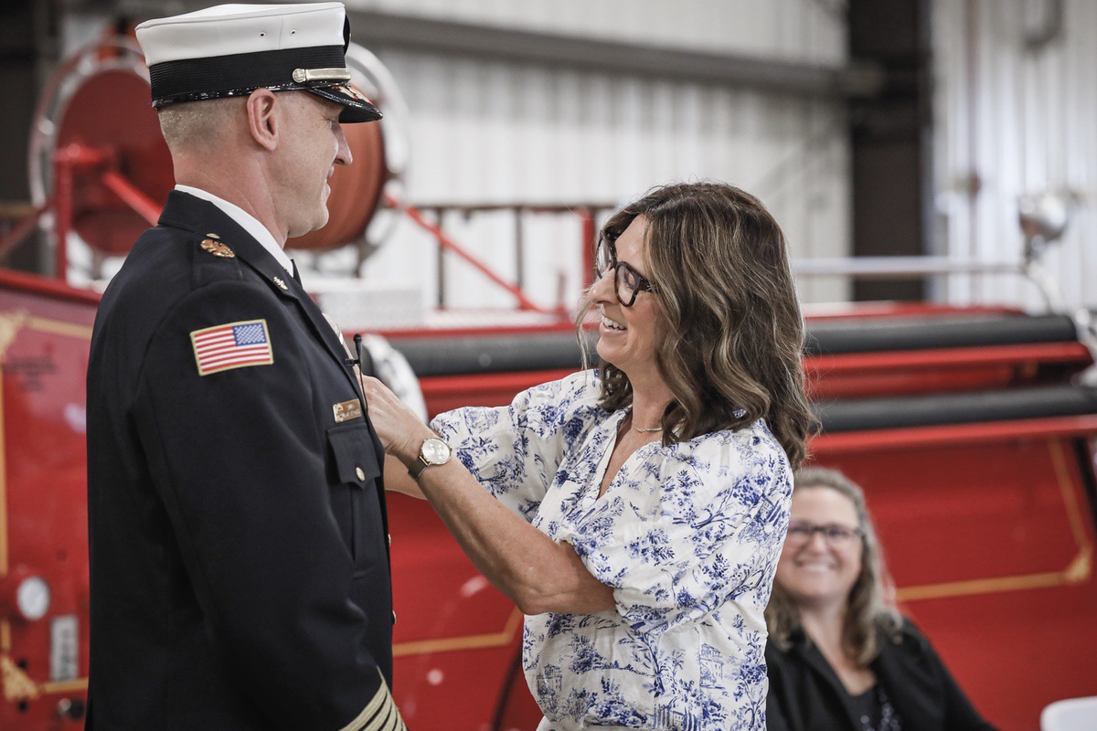 Dan Wagner’s wife, Sheila, pins new Fire Chief badge on Wagner’s uniform, during swear-in ceremony. (Photo by Steve Peterson/My Sun Day News)