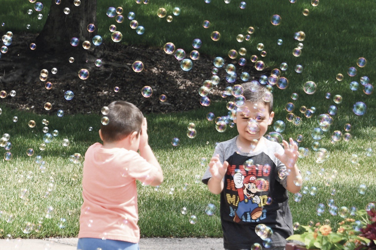 (L to R) Leo Garcia with older brother Marcos chase bubbles at the Grandma, Grandpa & Me’s annual picnic. (Photo by Christine Such/My Sun Day News)