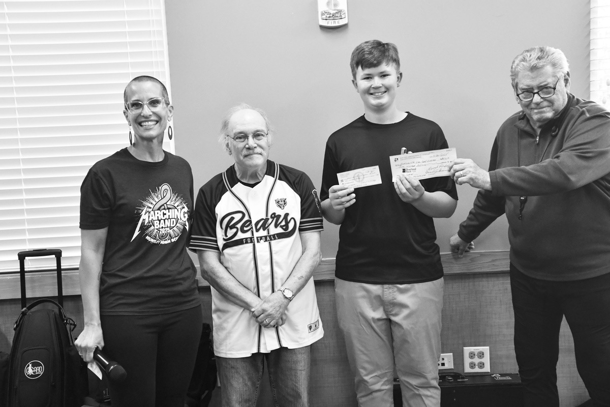 HHS Booster Deanna Reeves and student Kyle Wolf accept checks from the Sun City Concert Band.