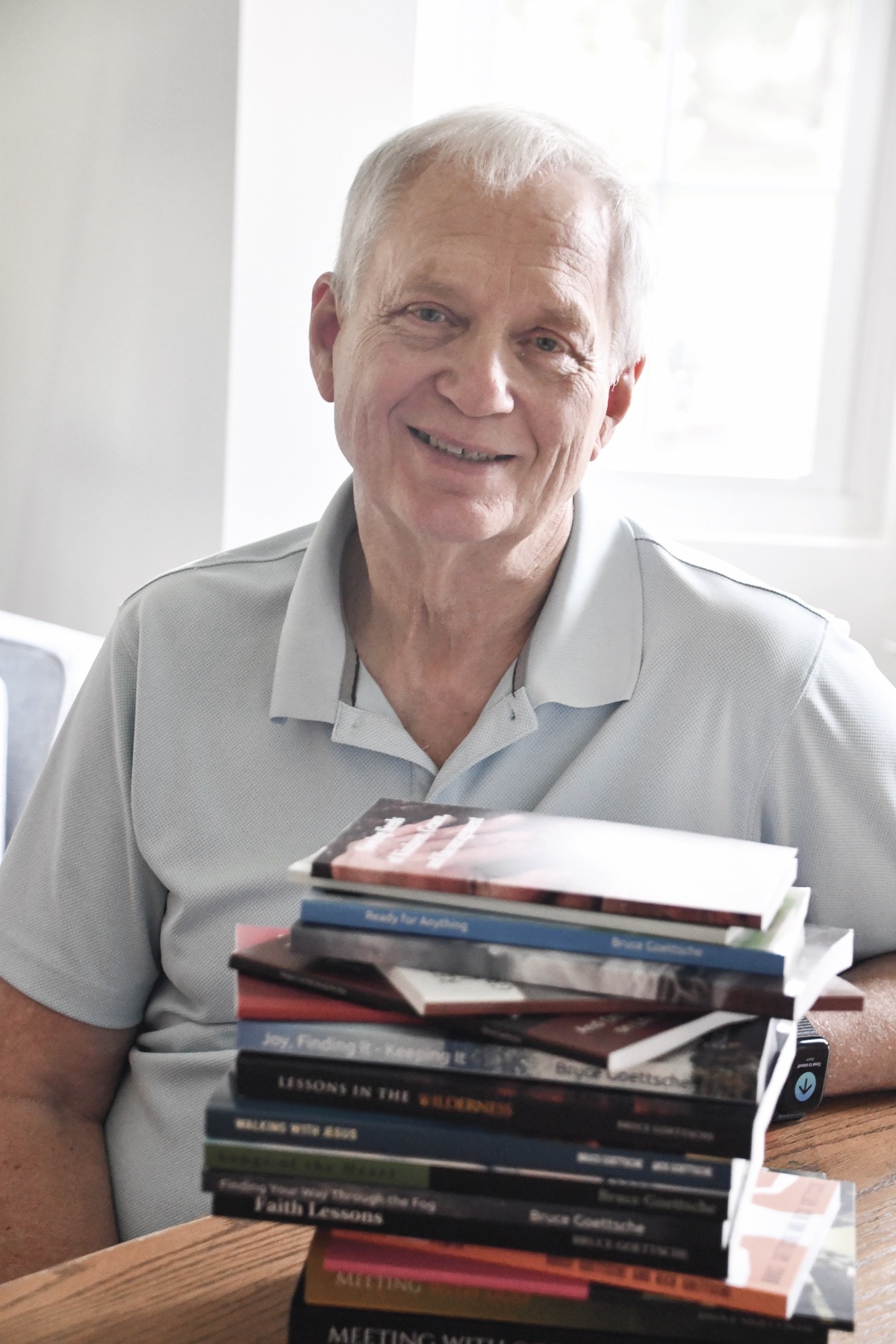 Reverend Bruce Goettsche poses here with a collection of his books. Throughout his pastoral career, Goettsche authored 23 books on Christian theology and daily living. (Photo by Christine Such/My Sun Day News)